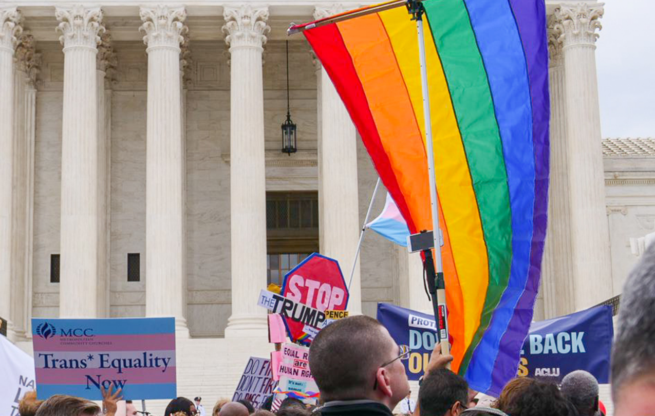 Gay pride flag in front of supreme court entrance with pro-LGBTQ equality signs